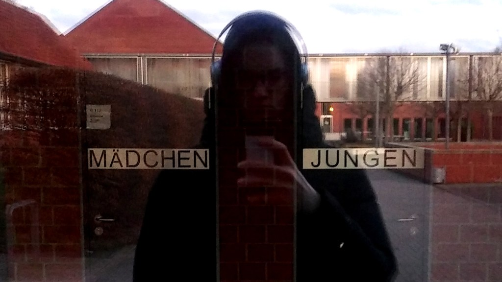 Sebastian Goddemeier ist für diesen Text zurück in seine Schule gefahren. Hier steht er zwischen den Türen des Mädchen- und Jungenklos.