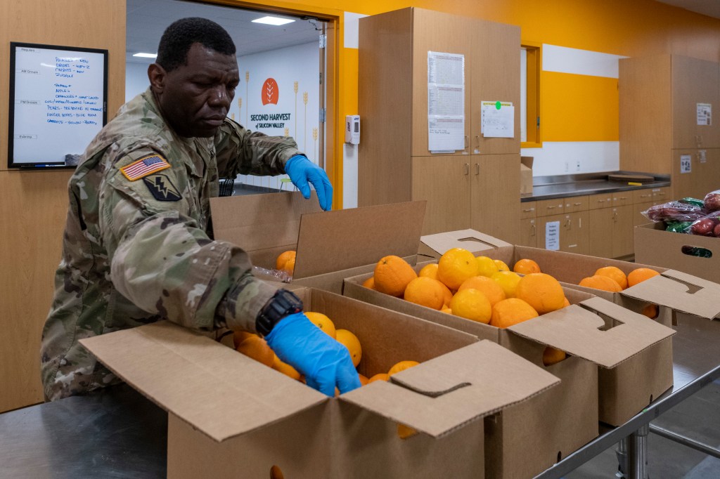 Members of the California National Guard Joint Task Force 115 help pack boxes of food at the Second Harvest Food Bank of Silicon Valley on March 25, 2020 in San Jose, California. (Photo by Yichuan Cao/Sipa USA)(Sipa via AP Images)​