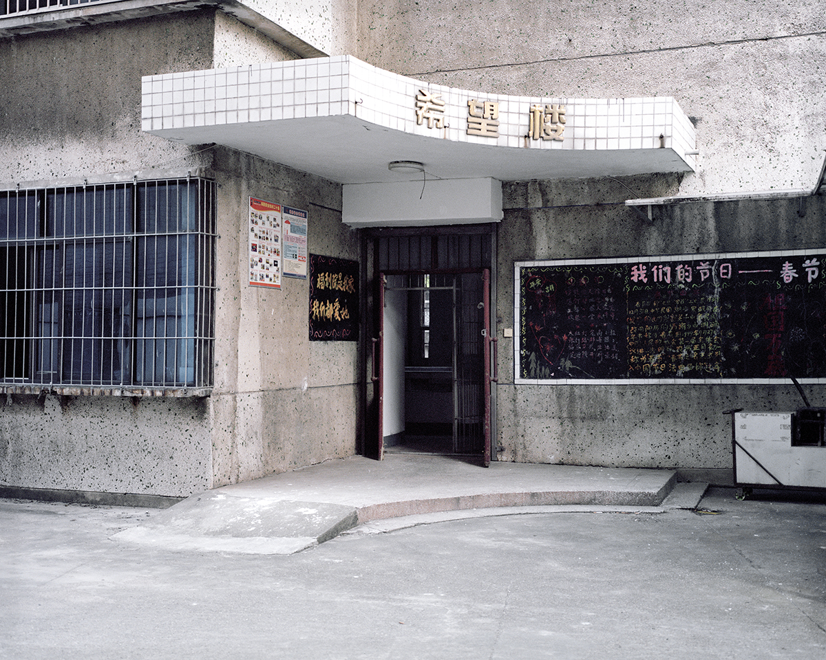 Der Eingang eines heruntergekommenen Waisenhauses, an den Wänden sind chinesische Schriftzeichen zu sehen