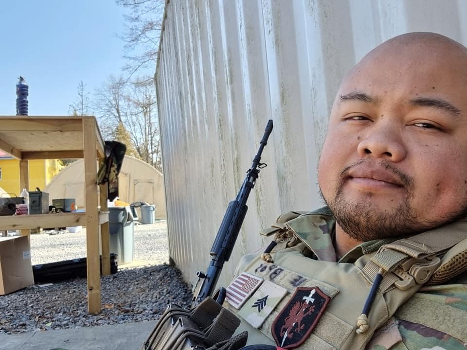 Ein junger Mann in Uniform mit US-Flagge an einen Metallcontainer gelehnt