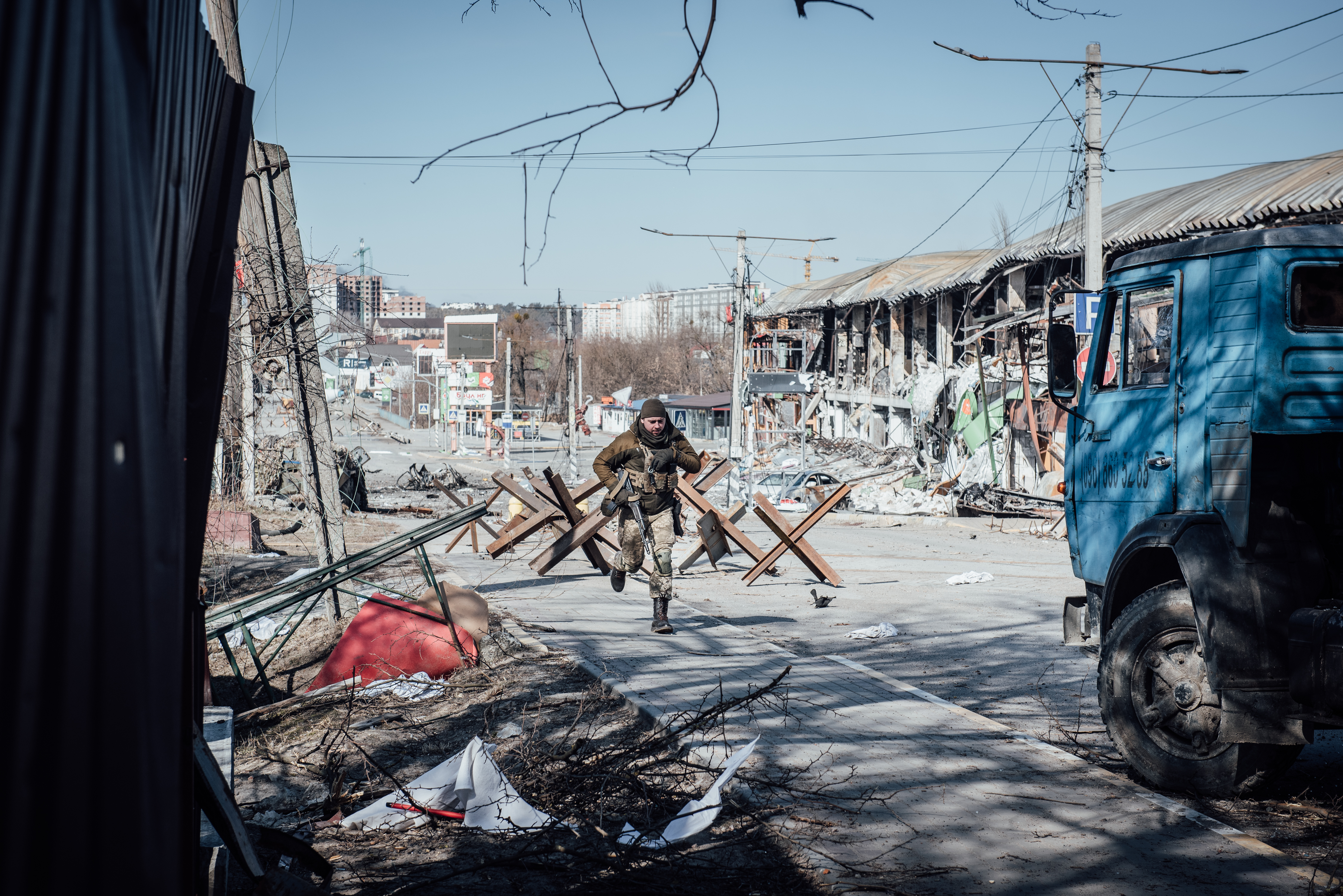 Adrien Vautier, Irpin, Ukraine – soldier running in the middle of a barricaded street unprotected.