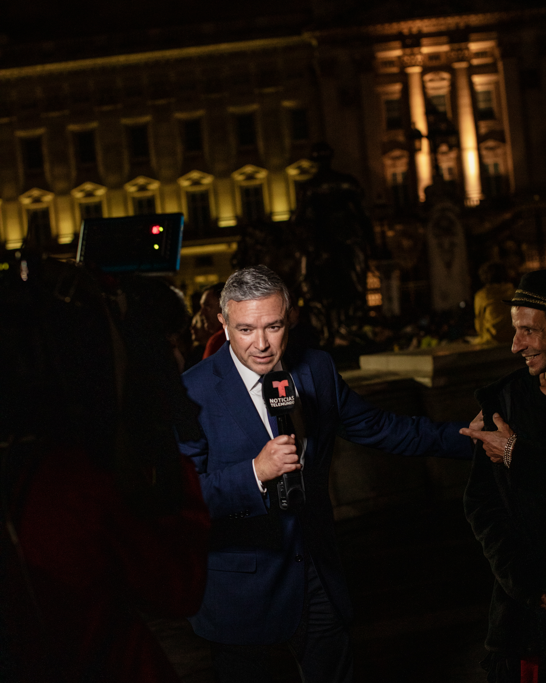 Un journaliste éclairé par la caméra devant le palais de Buckingham
