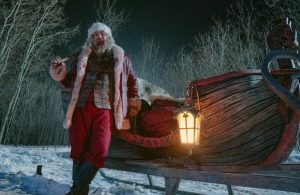 Der blutverschmierte Weihnachtsmann lehnt an seinem Schlitten. Im Film Violent Night tötet Santa Claus Verbrecher