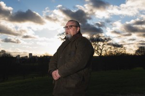 A man stands in front of a cloudy sky